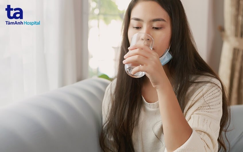 Bàn tay cầm cốc nước và viên thuốc cảm cúm Tamiflu