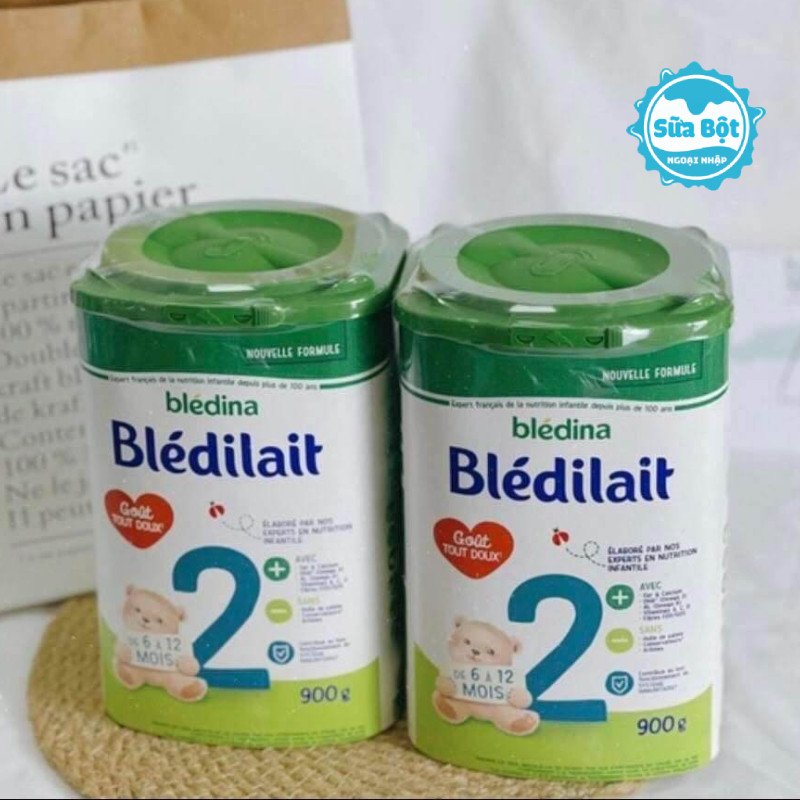 Bé đang chơi đùa vui vẻ bên cạnh hộp sữa Bledilait số 2 900g, biểu tượng cho sự phát triển khỏe mạnh.