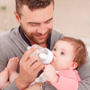 Bố cho bé bú bình, một trong những vật dụng thiết yếu cho bé