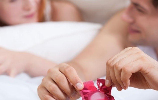 Cặp đôi nắm tay thể hiện sự tin tưởng và an toàn trong mối quan hệ, với bao cao su là biện pháp bảo vệ.