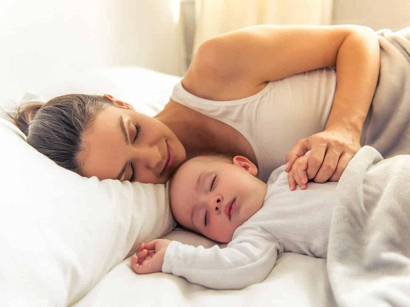Em bé nằm thoải mái trong nôi với chăn ấm, minh họa môi trường ngủ lý tưởng giúp vượt qua khủng hoảng ngủ 4 tháng.