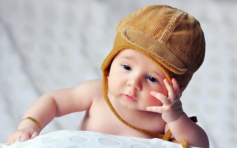 Em bé nằm trong nôi, tay vịn thành nôi, gương mặt lo lắng, thể hiện sự lo lắng chia ly