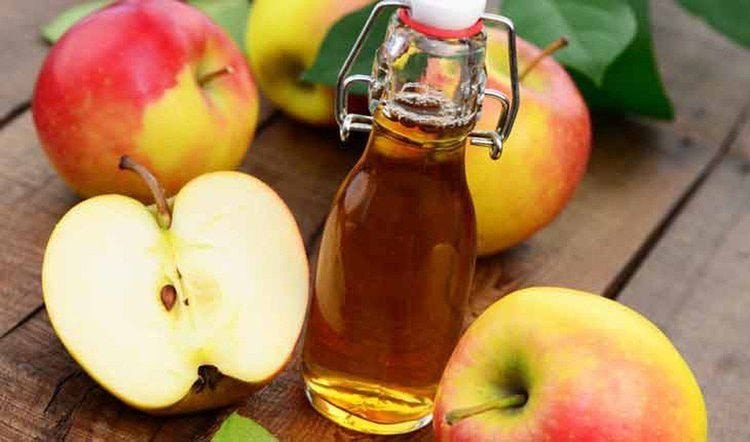 Một ly giấm táo lỏng với những trái táo tươi, minh họa lợi ích sức khỏe từ viên uống giấm táo.