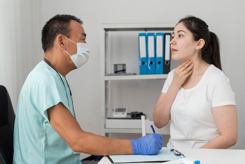 Người bệnh đang thảo luận với bác sĩ về tình trạng họng sau khi sử dụng xịt họng con ong, nhấn mạnh tầm quan trọng của việc tham khảo ý kiến chuyên gia