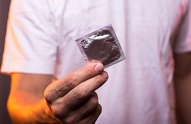 Người đàn ông cầm hộp bao cao su, biểu tượng cho sự an toàn trong quan hệ tình dục.