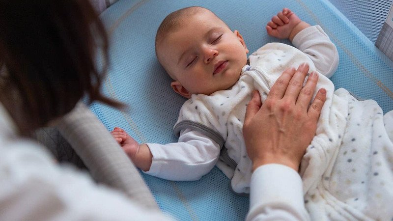 Người mẹ đang ôm con và vỗ về, tạo cảm giác an toàn và gắn kết cho bé