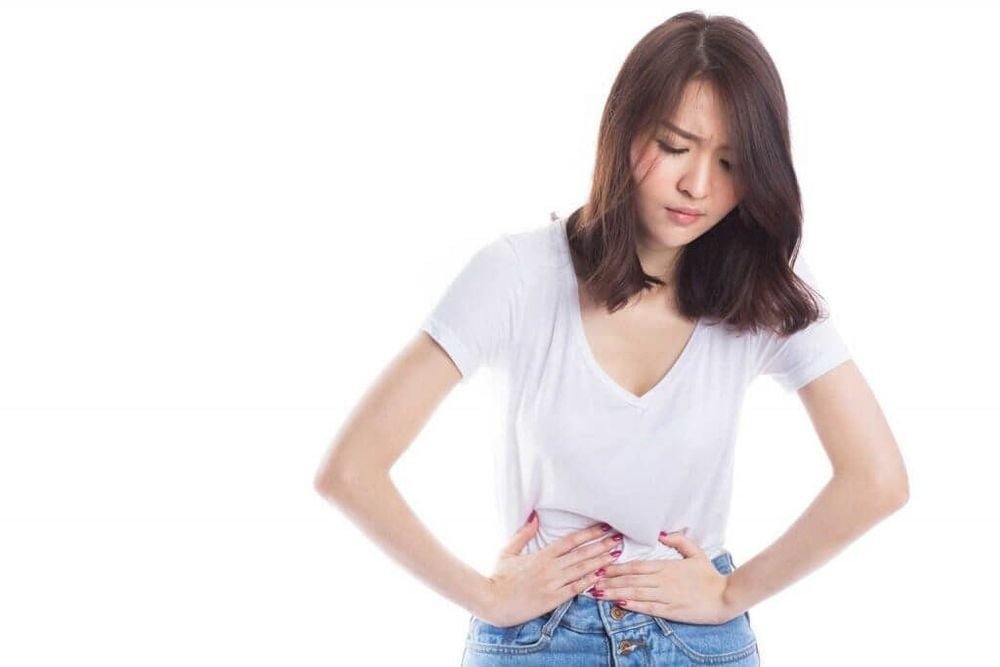 Người phụ nữ với biểu hiện khó chịu ở bụng, minh họa tác dụng phụ tiềm ẩn của viên uống giấm táo như khó tiêu.