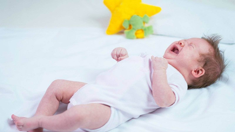 Trẻ nhỏ đang cố gắng ngủ trong nôi, bé có biểu hiện khó ngủ và trằn trọc